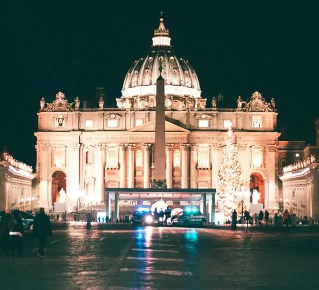 St. Peter's Basilica illuminated at night with the Vatican Christmas tree in St. Peter's Square