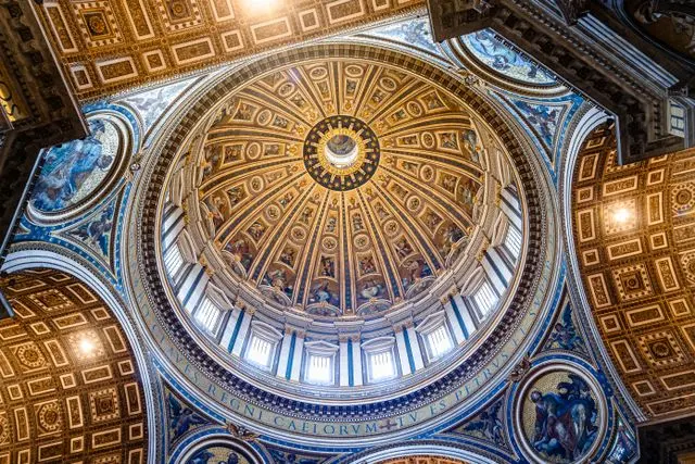Interior view of St. Peter's Basilica dome with ornate Renaissance artwork and gilded ceiling