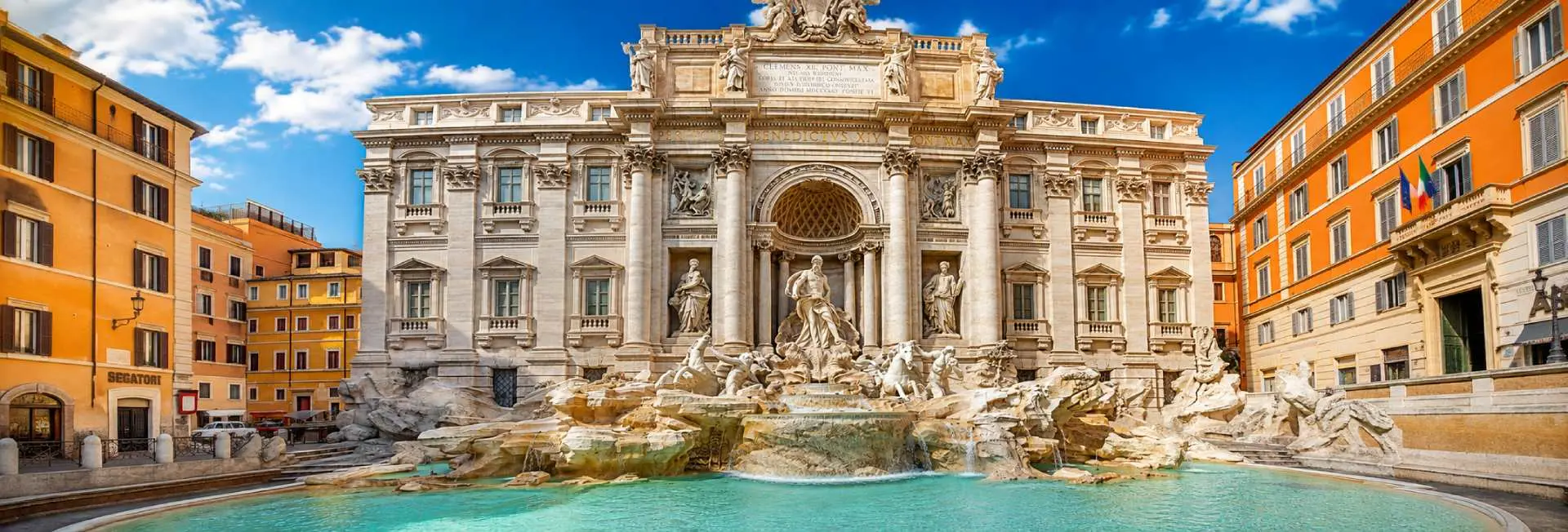 Trevi Fountain in Rome with Baroque sculptures, turquoise water, and historic buildings under a bright blue sky.