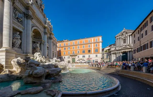 Side view of Trevi Fountain with visitors gathered around the iconic landmark in Rome.