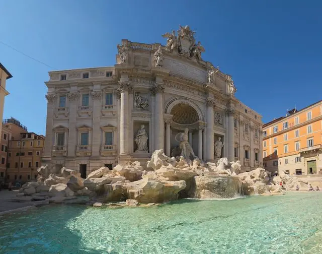 Front view of Trevi Fountain featuring Baroque sculptures and turquoise waters in Rome.