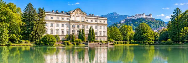 Leopoldskron Palace in Salzburg, Austria, reflected in the lake with scenic Alpine surroundings.