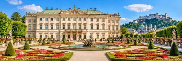 Mirabell Palace and Gardens in Salzburg with colorful flowers and Hohensalzburg Fortress in the background.