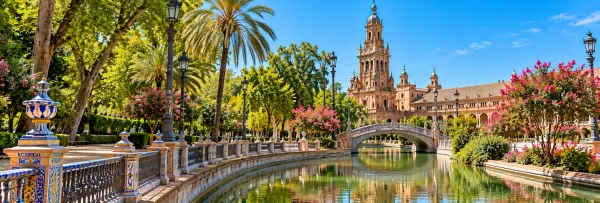 Parque de María Luisa in Seville, Spain, featuring a scenic canal, ornate bridge, and lush gardens.