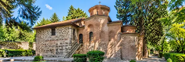 Boyana Church in Sofia, Bulgaria, featuring medieval stone and brick architecture surrounded by lush greenery.
