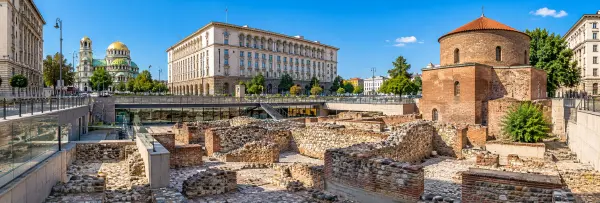 Ancient Roman ruins at Serdica Archaeological Complex in Sofia, Bulgaria, surrounded by historic city buildings.