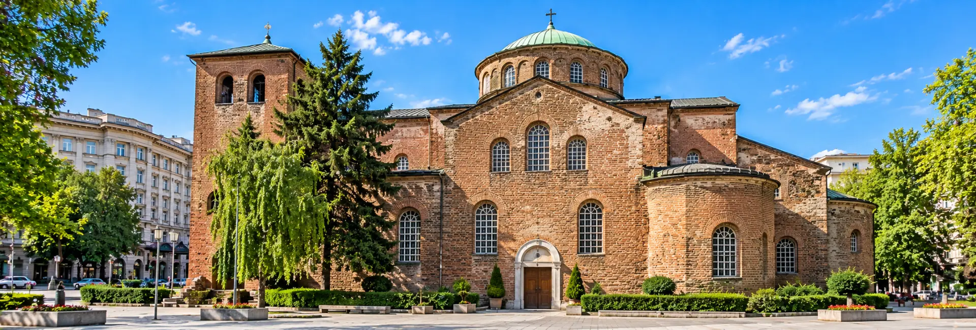 St. Sofia Church in Sofia, Bulgaria, featuring historic red-brick architecture, arched windows and a peaceful setting.