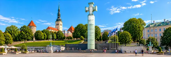 Freedom Square in Tallinn, Estonia, featuring the Cross of Liberty monument, Estonian flags and historic buildings.