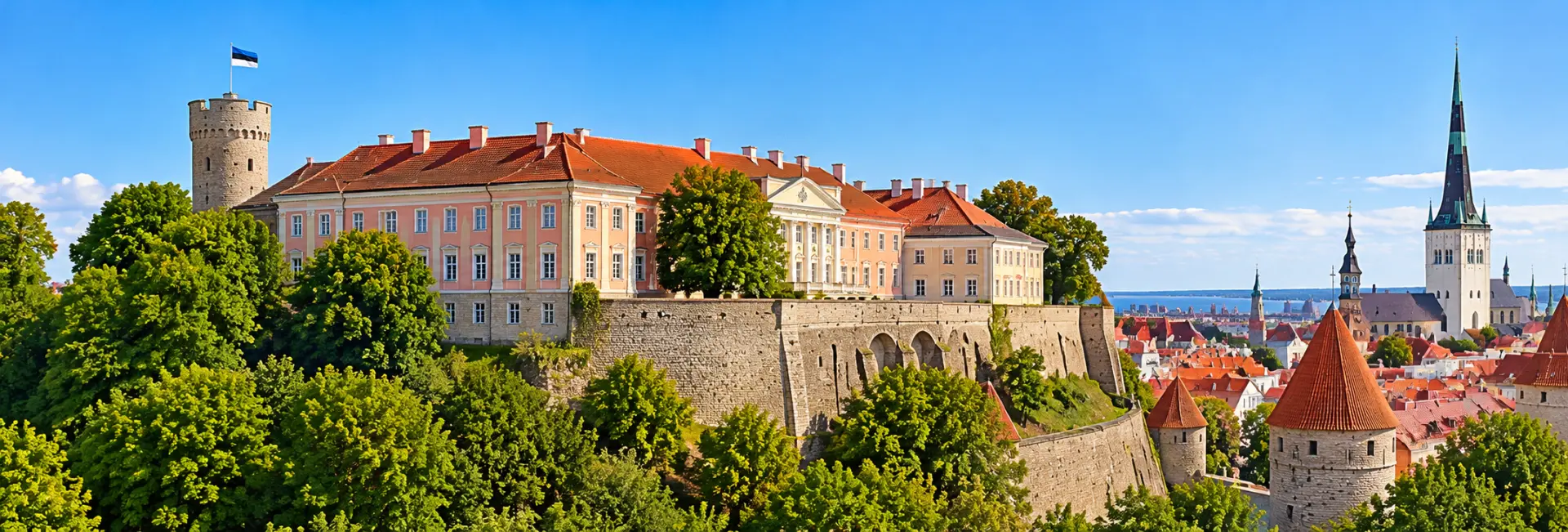 Panoramic view of Toompea Castle in Tallinn, Estonia, featuring its pink facade, historic towers and stone walls.