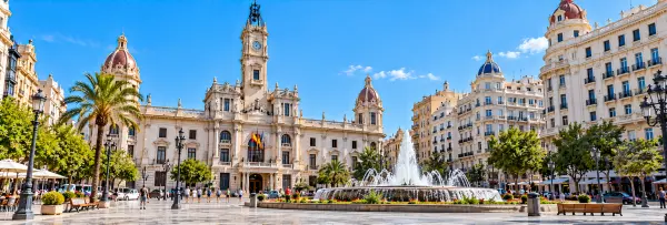 Plaza del Ayuntamiento in Valencia, Spain, featuring ornate historic buildings and a central fountain.