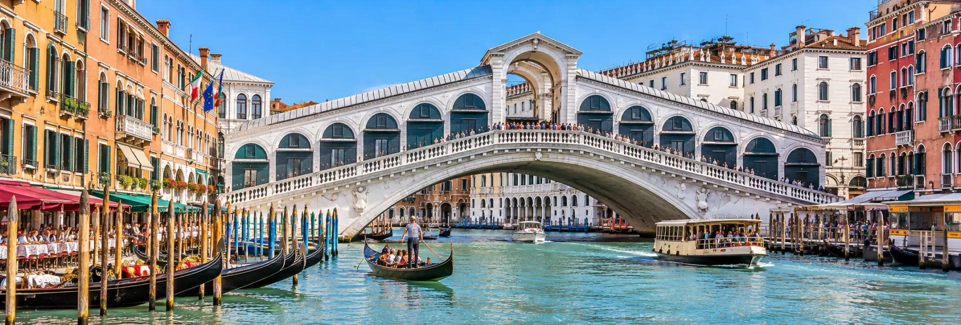 Rialto Bridge in Venice, Italy, spanning the Grand Canal amid historic palaces and gondolas.
