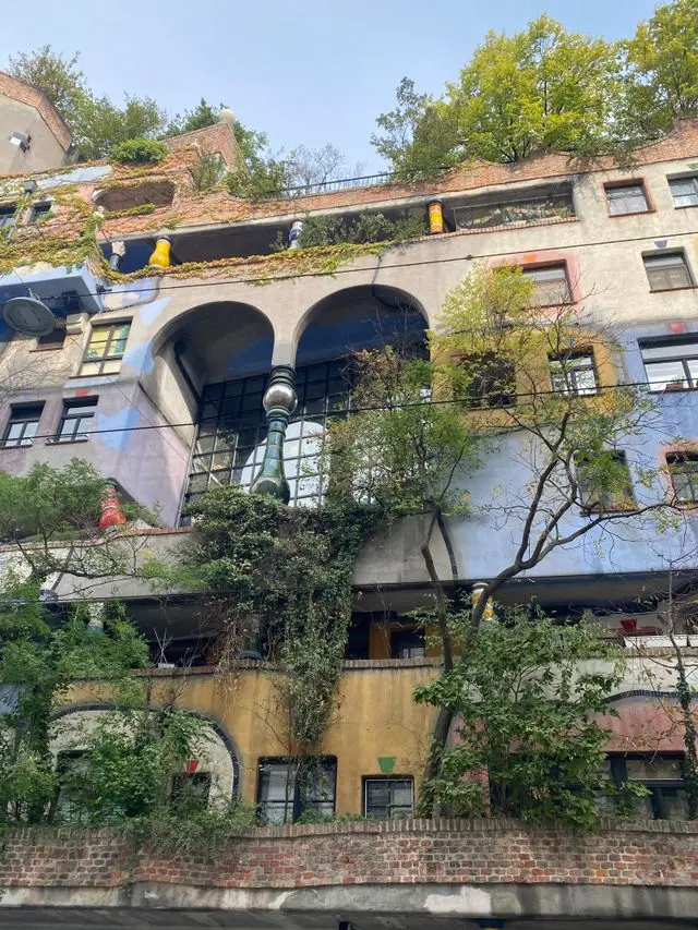 Hundertwasserhaus façade with arched balconies, rooftop greenery, and colorful ceramic details