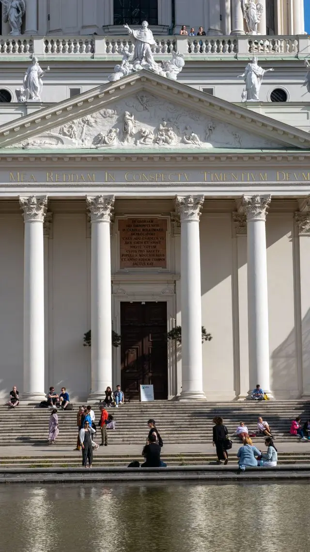Karlskirche façade in Vienna with Baroque sculptures, columns and Latin inscription