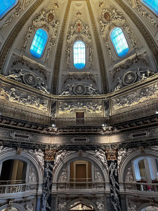 Elaborately decorated interior dome with sculptures and stained-glass windows at Kunsthistorisches Museum