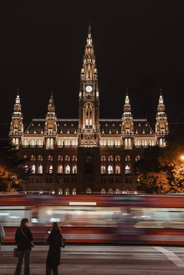 Vienna City Hall (Rathaus) illuminated at night with a tram passing in front