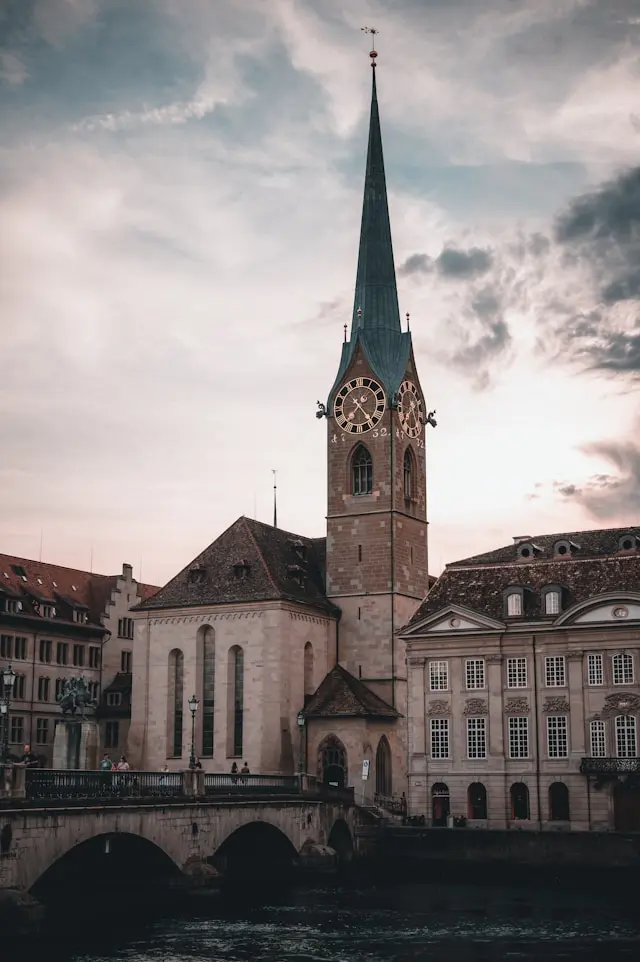 Fraumünster Zurich with its tall green spire, clock face and riverside architecture