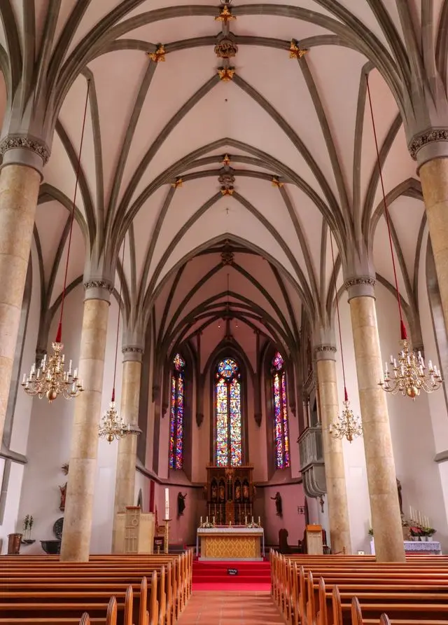 Interior of Fraumünster Zurich with vaulted arches, chandeliers and colorful stained-glass windows