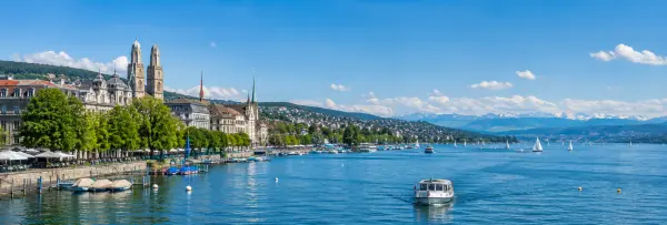 Lake Zurich with sailboats, waterfront promenade, Zurich skyline and distant Swiss Alps