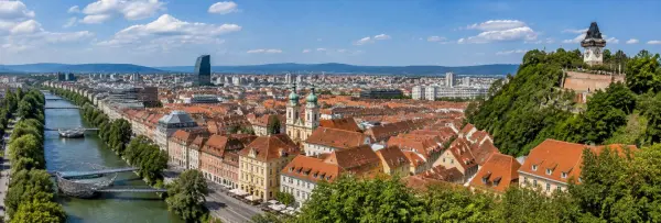 Graz Austria skyline with historic red rooftops, Mur River and Schlossberg Clock Tower