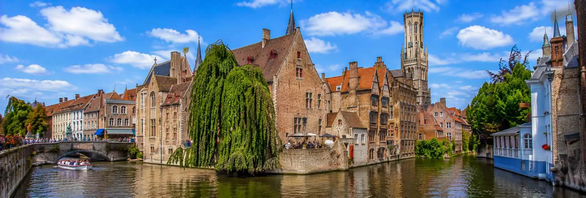 Bruges Belgium canal with medieval buildings, stone bridge and historic Belfry