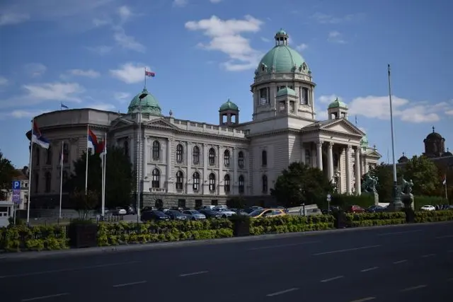 National Assembly of Serbia in Belgrade, featuring a grand neoclassical building with green domes and tall columns.