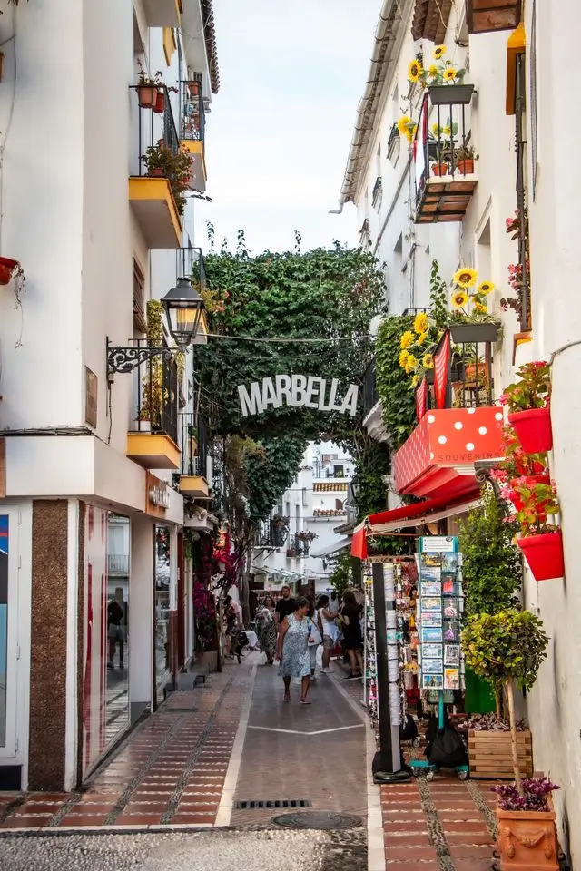 Charming whitewashed street in Marbella Old Town with flowers and a Marbella sign
