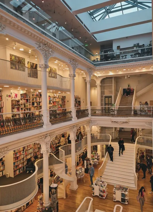 Interior of Cărturești Carusel bookstore in Bucharest, featuring elegant white balconies, bookshelves, and staircases.