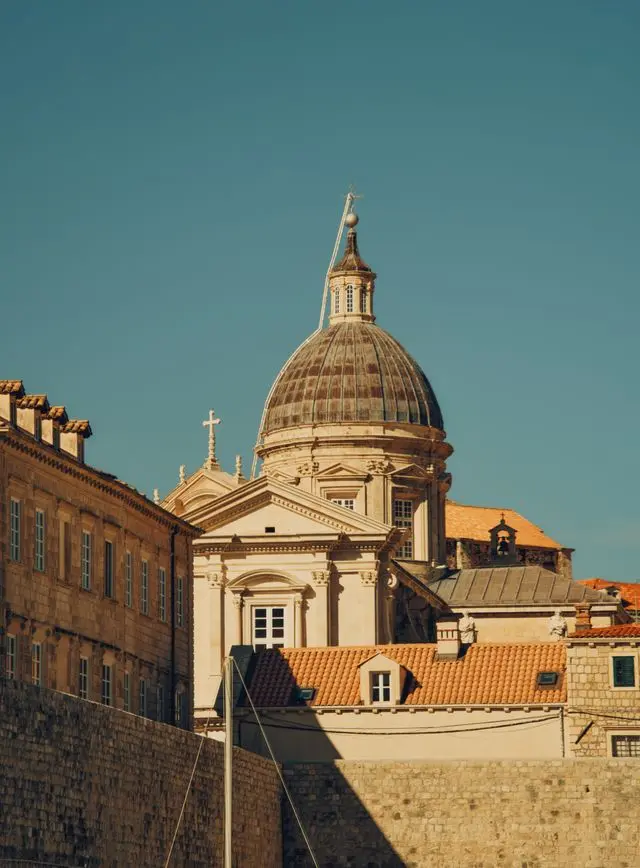 Dubrovnik Cathedral in Croatia, featuring a grand Baroque dome, historic stone buildings, and red-tiled rooftops.
