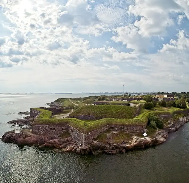 Historic stone fortifications and grassy ramparts along the rocky coastline of Suomenlinna, Helsinki.