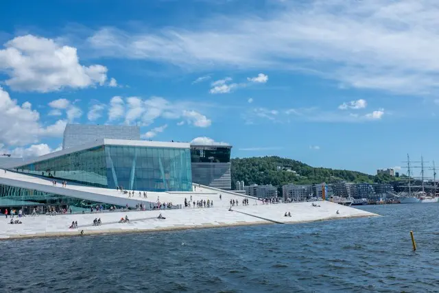 Oslo Opera House beside the Oslofjord, featuring modern architecture and a sloping rooftop.