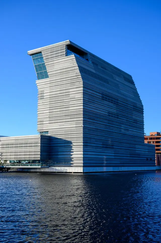 Modern angular waterfront architecture in Oslo, Norway, reflected in the calm blue water.