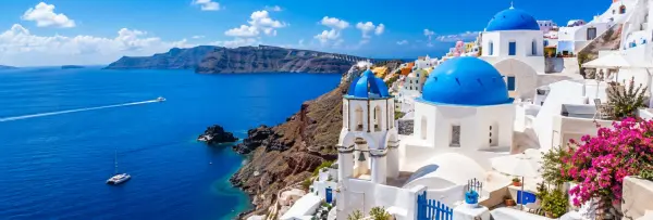 Panoramic summer view of Santorini, Greece, featuring iconic whitewashed buildings with blue-domed churches overlooking