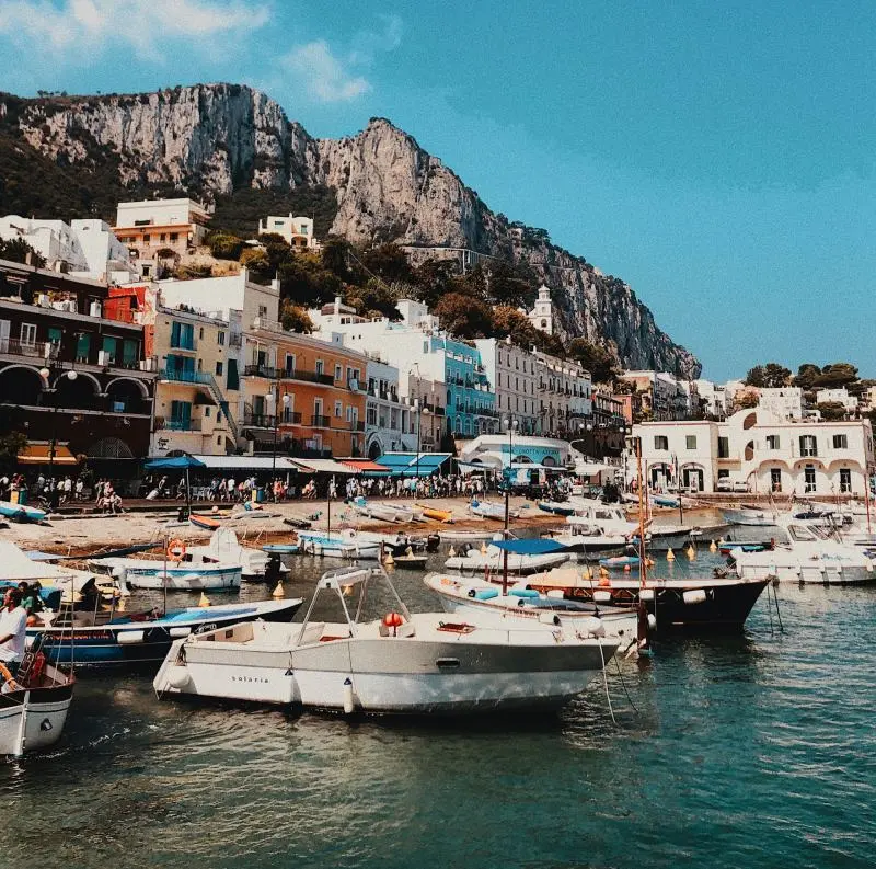 Colorful Marina Grande harbor with boats and dramatic cliffs on Capri Island, Italy