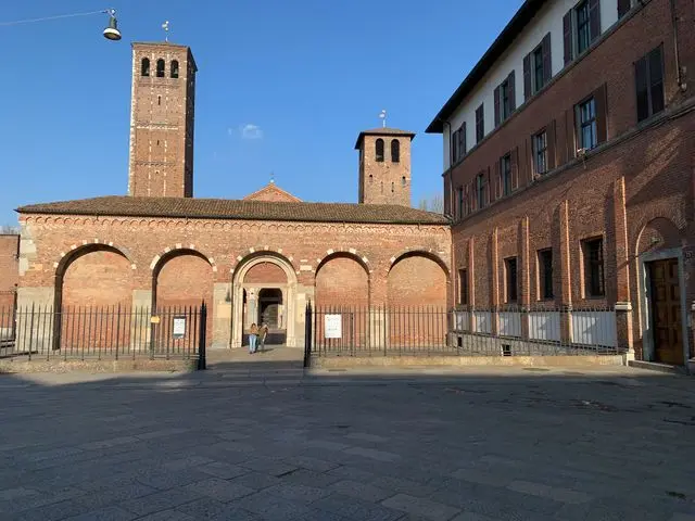 Historic red-brick church complex with tall medieval bell towers in Milan.