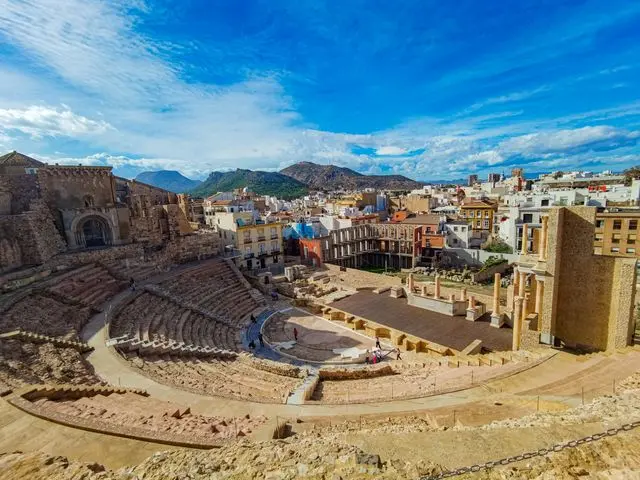 Ancient Roman Theatre in Málaga, Spain, featuring semicircular stone seating, historic ruins, and surrounding city build