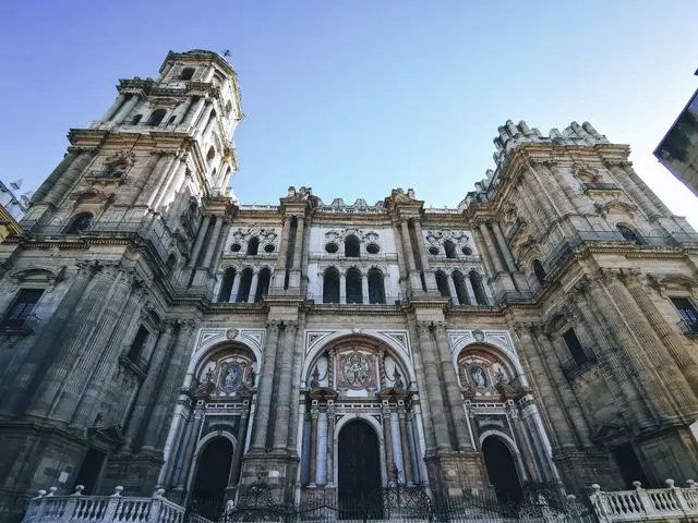 Málaga Cathedral in Spain, featuring an ornate Renaissance facade, towering bell tower, and grand stone entrance.