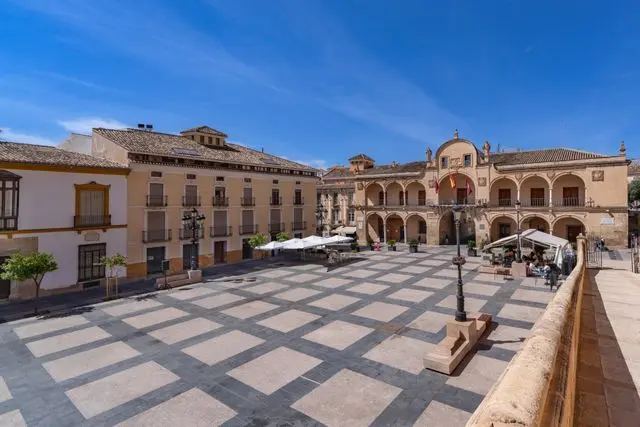 Historic town square in Mallorca, featuring a stone-paved plaza, traditional buildings, and an ornate civic facade.