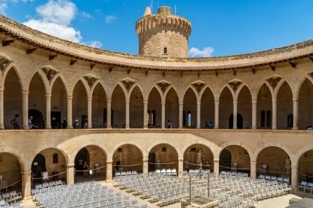 Interior courtyard of Bellver Castle in Mallorca, featuring circular Gothic architecture, stone arches, and a central to