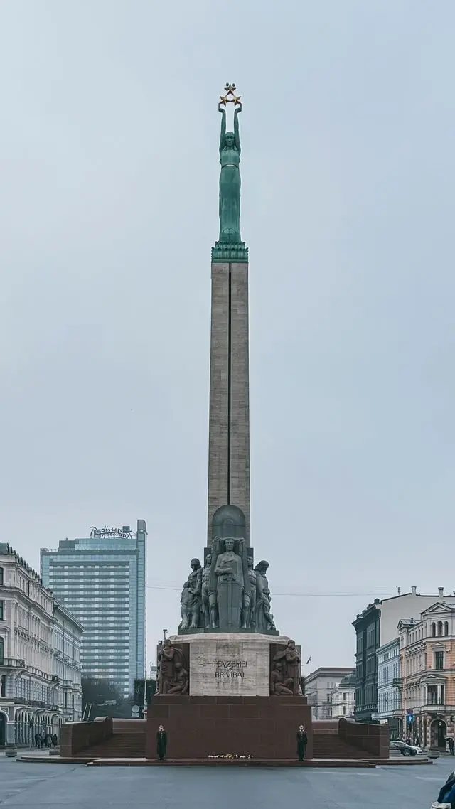 Freedom Monument in Riga, Latvia, featuring a tall stone column topped by a bronze statue holding three golden stars.