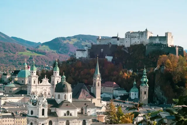 Panoramic view of Salzburg Old Town with historic church domes and Hohensalzburg Fortress on the hill.