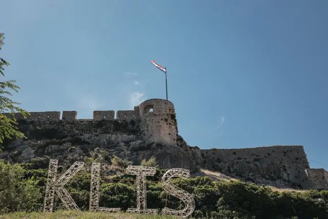 Klis Fortress near Split, Croatia, featuring medieval stone walls, a Croatian flag, and a hilltop setting.