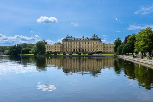 Drottningholm Palace reflected in the water surrounded by green gardens in Stockholm