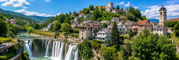Jajce Pliva Waterfall with historic houses, medieval fortress and green mountains in Bosnia and Herzegovina