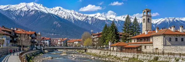 Bansko historic town with traditional houses, Holy Trinity Church and snow-capped Pirin Mountains in Bulgaria.
