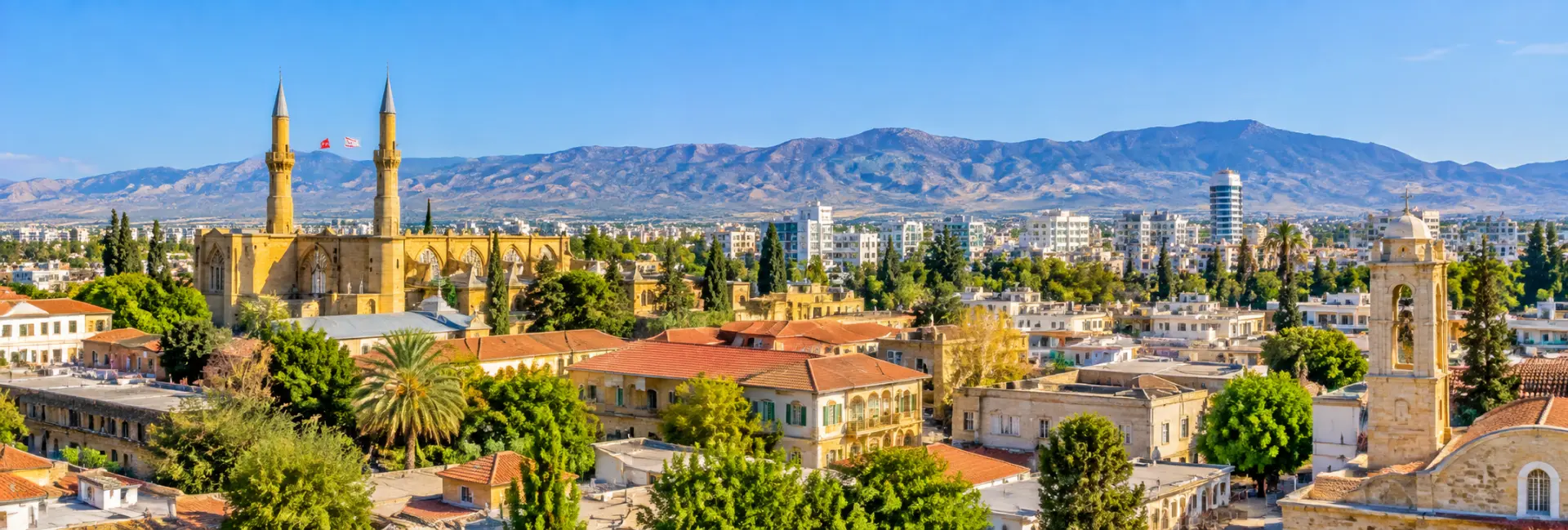 Panoramic view of Nicosia, Cyprus, featuring historic architecture, minarets, red-tiled roofs, and mountain scenery.