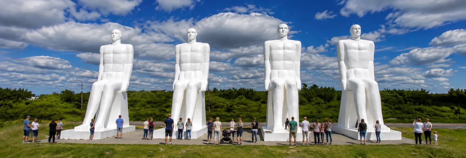 Four giant white statues with tourists at Man Meets the Sea in Esbjerg, Denmark