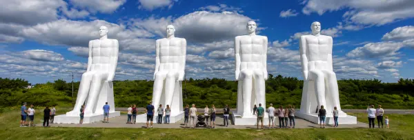 Four giant white statues with tourists at Man Meets the Sea in Esbjerg, Denmark