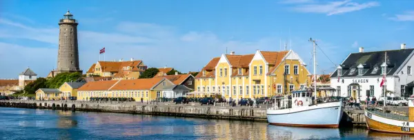 Skagen, Denmark harbor with colorful waterfront buildings, boats, and a historic lighthouse