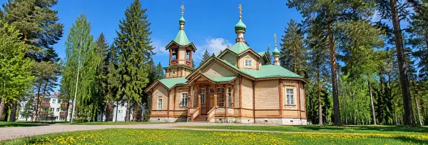 Traditional wooden Orthodox church in Joensuu, Finland, surrounded by pine trees