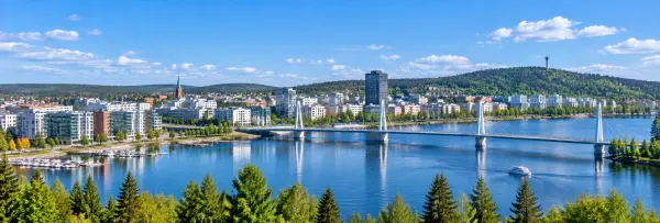 Panoramic view of Jyväskylä, Finland, featuring Lake Jyväsjärvi, modern city buildings, a bridge, and forested hills.